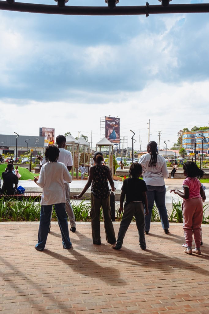 Five visitors stand on a brick terrace looking across the outdoor mall area.