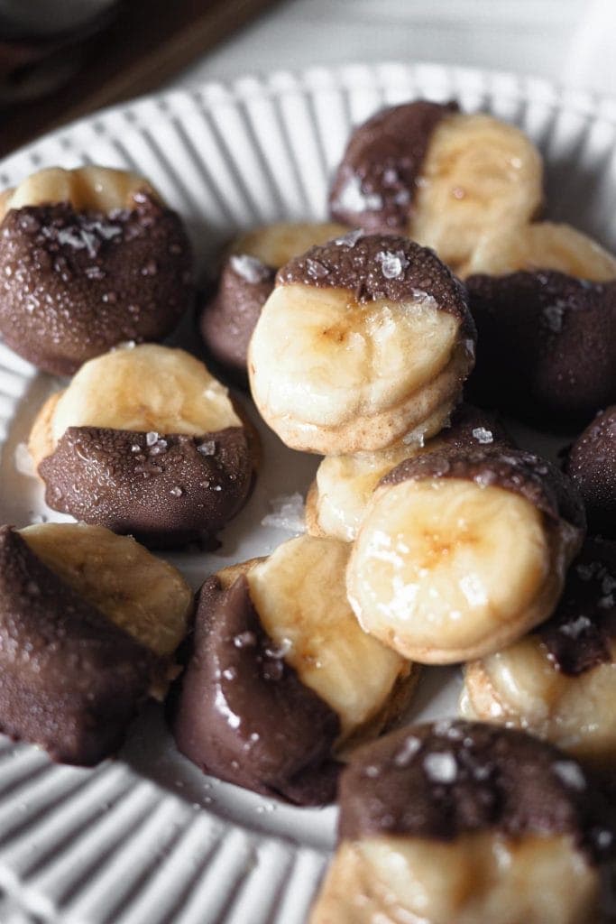 Estos deliciosos Bocaditos Helados de Crema de Almendra Plátano y Chocolate, son un snack perfecto. Son unos caprichitos saludables ideales para los días de verano y, ya que son del tamaño de un bocado, podemos considerarlos bajos en calorías (si logras no comerte más de 1 o 2 a la vez). Esta foto se ha tomado de cerca para ver los detalles, hasta se puede apreciar la condensación.