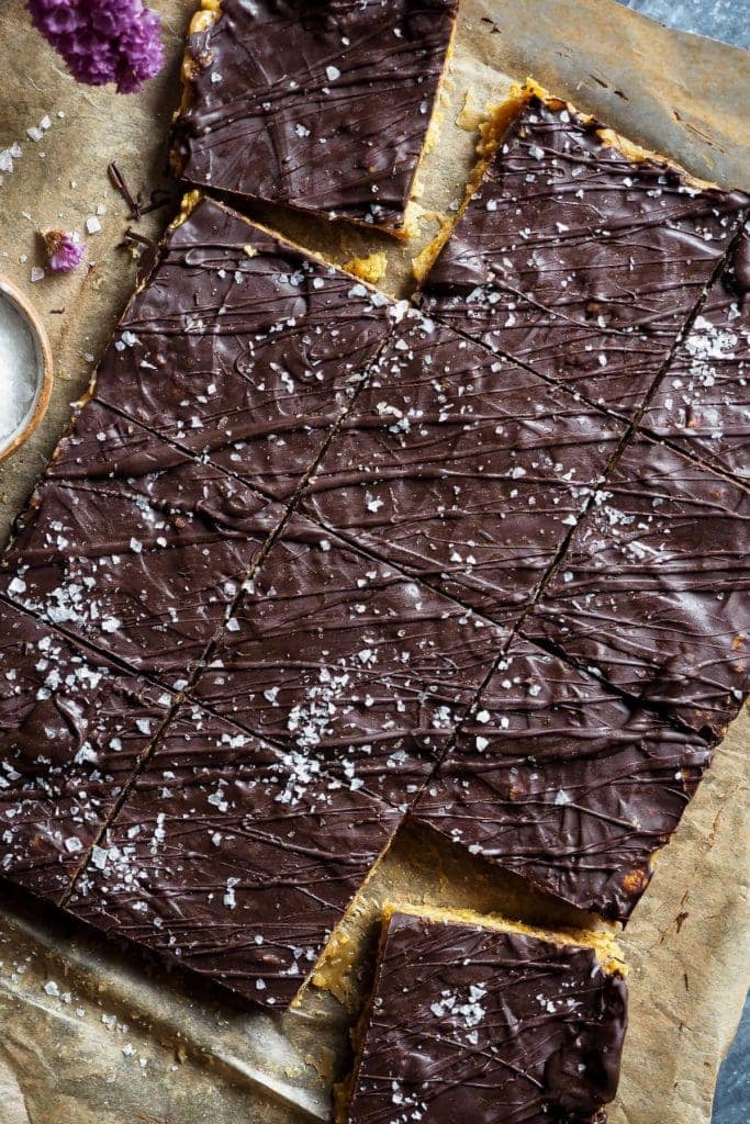 Healthy-ish Cornflakes and Nut Butter Bars, naturally gluten-free and vegan. They are easy and simple to make, and with that chocolate top, they are just the perfect snack. In this overhead shot, the bars are cut in squares and the top left and bottom right corners have been slightly moved away from the rest. The bars are placed diagonally with respect to the picture.