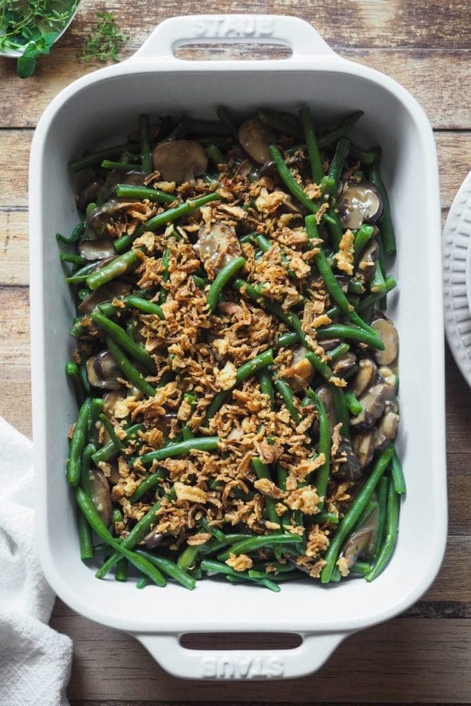 The green bean casserole you'll need in summer! Fresh green beans to make the most of summer produce, dairy-free mushroom sauce, yet creamy and delicious, and a crispy onion top, all made under 20min. Guaranteed side dish hit! An oven safe dish with the green bean and mushroom sauce mixture can be seen in the shot, topped with the crispy fried onion.