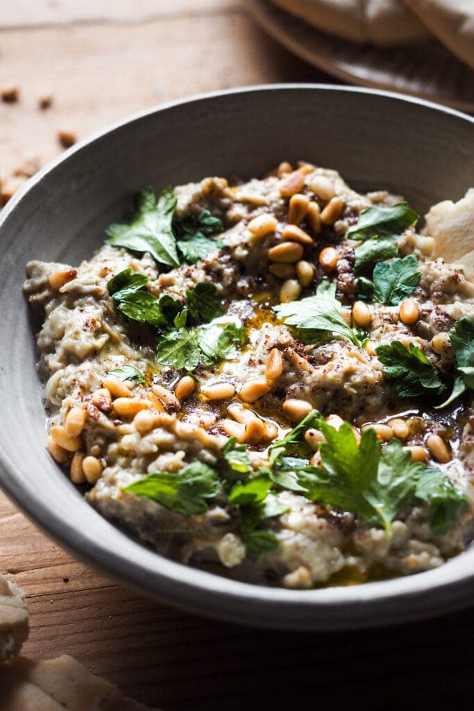 El Mutabal es un dip de berenjena muy parecido al Baba Ganoush con la gran diferencia de que el primero lleva tahini y no lleva melaza de granada. Es un aperitivo ideal o snack saludable, incluso va genial como acompañamiento. Es un dip cremoso, con un sabor meloso gracias a ese toque ahumado de la berenjena asada. Además es vegano (o se puede adaptar fácilmente), sin gluten y lo mejor, muy fácil de hacer. Acompáñalo de verduras o algún tipo de pan plano y listos, ya solo queda disfrutarlo. | Receta de Paula's Apron