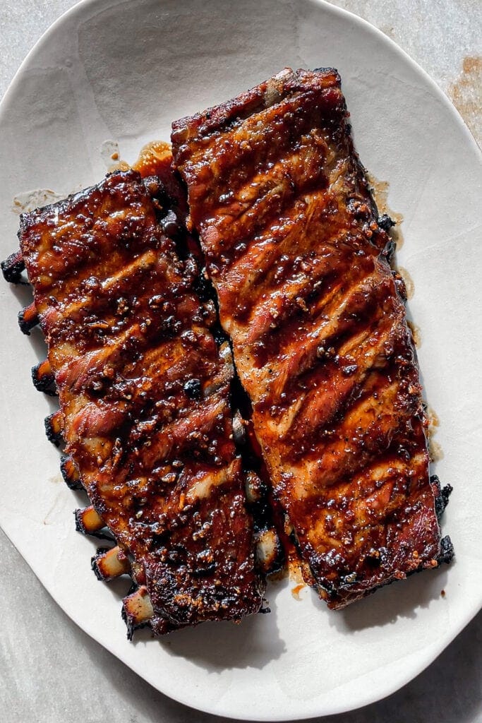 Paula's Apron Costillas de Cerdo al Horno al Estilo Asiático Hacer costillas de cerdo al horno jugosas no puede ser más fácil, pero eso sí, piden paciencia ya que toda la magia ocurre haciéndolas lentamente en el horno. Hoy concretamente te traigo mi receta de Costillas de Cerdo al Horno al Estilo Asiático, con toque de soja, miel, jengibre y ajo. ¡Quedan literal para chuparse los dedos! Es una comida ideal para cuando tienes poco tiempo para estar en la cocina pero sabes que estarás ajetreado con cosas por casa o trabajo en remoto, las preparas en 5 minutos y te olvidas de ellas hasta que llegue la hora de comer. Pan, patatas o arroz para acompañar y ¡a disfrutar! | Receta de Paula's Apron