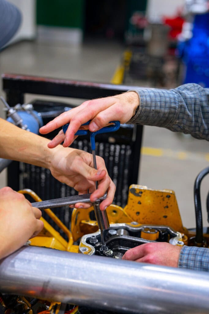 Hands of two people working on an engine.