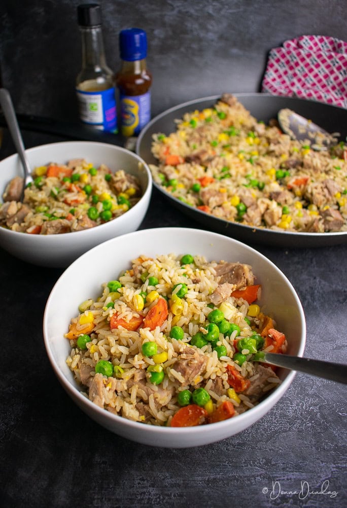 Pork Fried Rice in bowls. Sauces and frying pan in background.