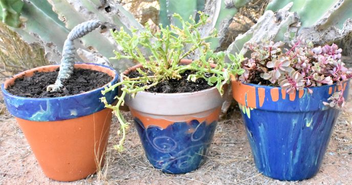 3 terracotta pots that have been decorated with acrylic pouring