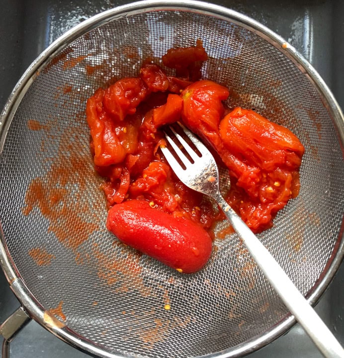 Bright red tinned tomatoes in a sieve