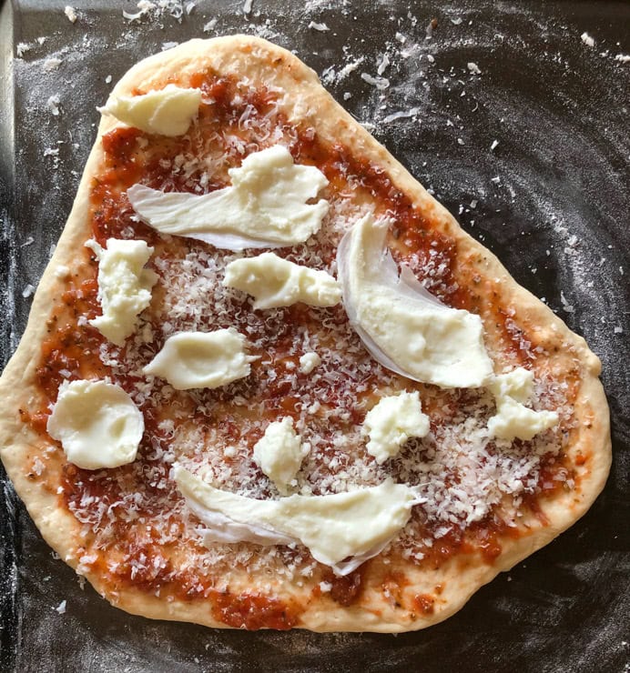 Uncooked pizza on a tray ready to go into the oven.