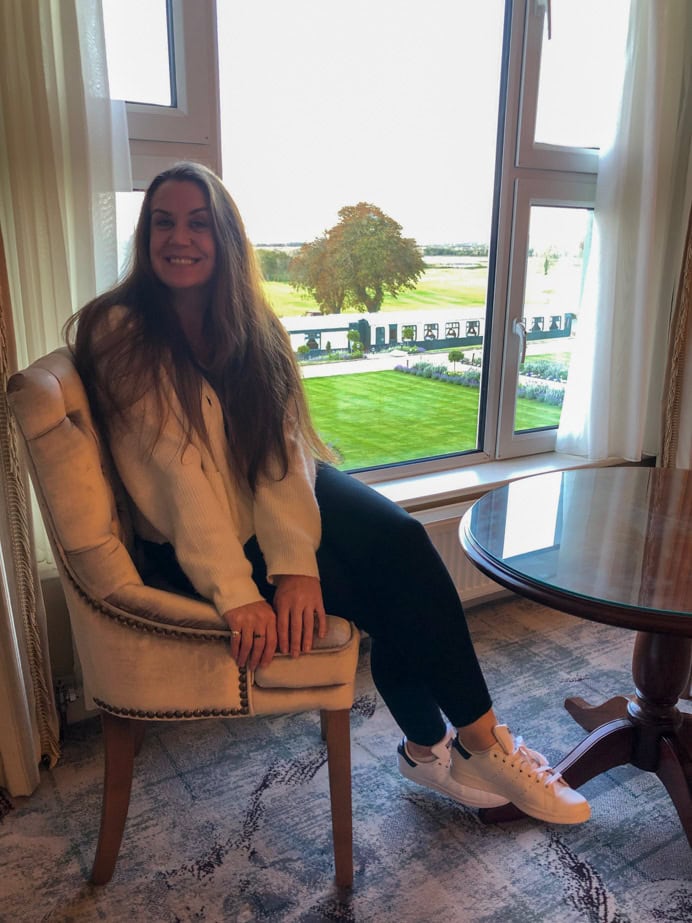 Melanie May sitting in a chair in the Glenlo Abbey Hotel and Estate Grand Suite