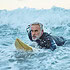 Beach, surfer and old man on surfboard swimming in nature enjoying dangerous water sports and retir
