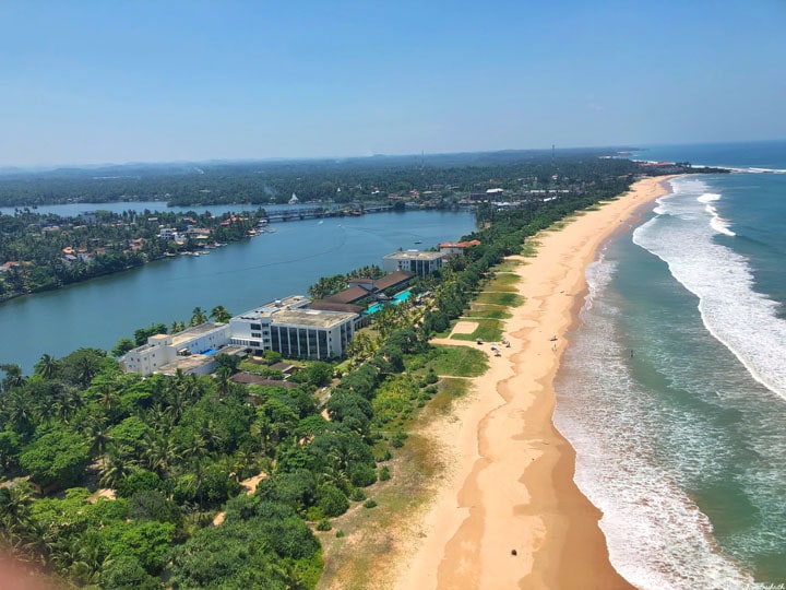 patch of land with buildings and trees between lake and bindian ocean at bentota seen from above