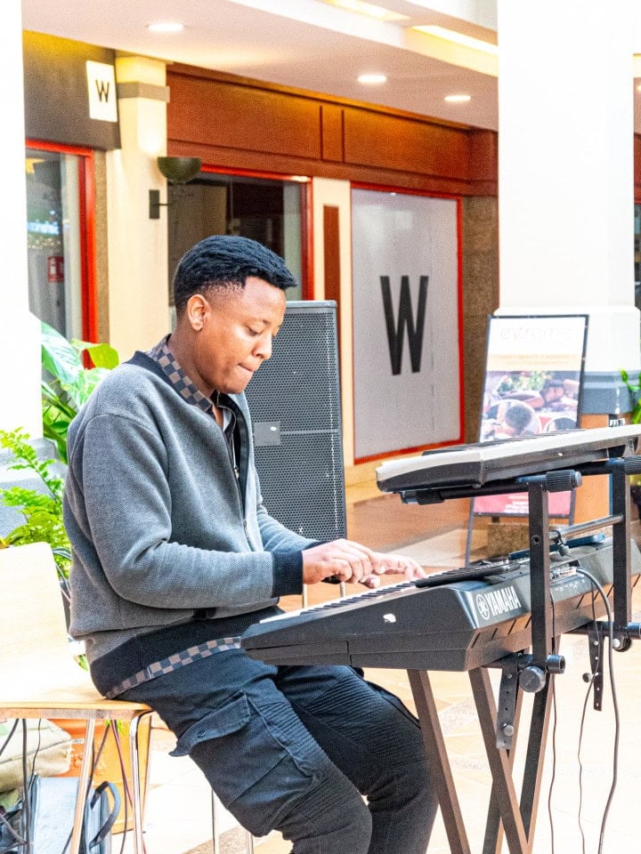Musician seated and playing an electronic keyboard indoors