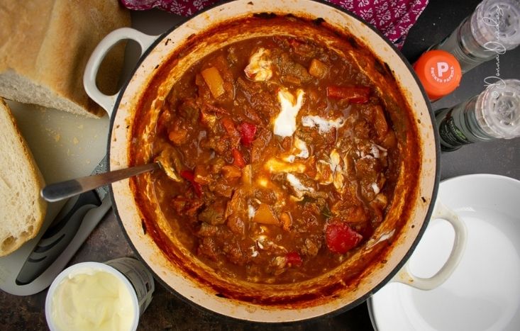 Beef Goulash with swirl of soured cream in cast iron dish.