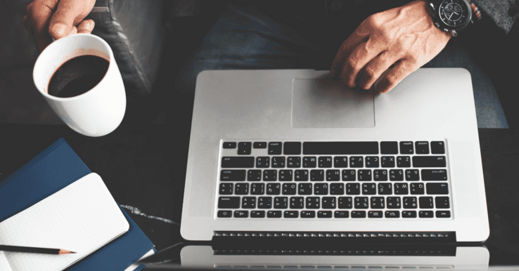 B2B marketer sips coffee at laptop while working on new lead generation tactics