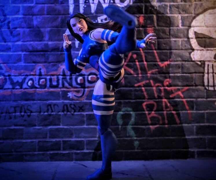 Psylocke Marvel Legends action figure delivering a high kick in front of urban graffiti wall with dramatic lighting