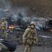 TOPSHOT - Ukrainian service members look for and collect unexploded shells after a fighting with Russian raiding group in the Ukrainian capital of Kyiv in the morning of February 26, 2022, according to Ukrainian service personnel at the scene. - Ukrainian soldiers repulsed a Russian attack in the capital, the military said on February 26 after a defiant President Volodymyr Zelensky vowed his pro-Western country would not be bowed by Moscow. It started the third day since Russian leader Vladimir Putin unleashed a full-scale invasion that has killed dozens of people, forced more than 50,000 to flee Ukraine in just 48 hours and sparked fears of a wider conflict in Europe. (Photo by Sergei SUPINSKY / AFP)