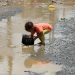 A boy washes a cooking pot in a rain water pool outside a slum area for the Muhamasheen (marginalized) community in Sanaa, Yemen July 26, 2020. Picture taken July 26, 2020. REUTERS/Khaled Abdullah - RC2W2I9BRGSW