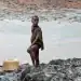A boy with a fishing net stands on the oil-soaked bank of a creek area in the Niger Delta: children are particularly susceptible to environmental pollutants, absorbing it into their tissue more rapidly than adults. Image by Milieudefensie via Flickr (CC BY-NC-SA 2.0).