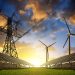 Solar panels with wind turbines and electricity pylon at sunset. Clean energy concept.