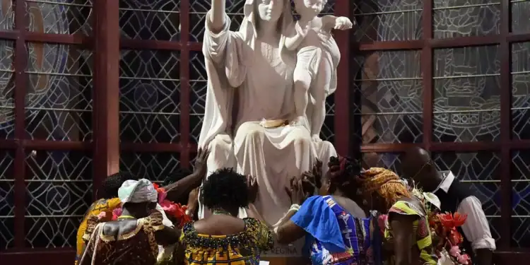 Catholic pilgrims pray next to a statue of the Virgin Mary at the Our Lady of the Peace