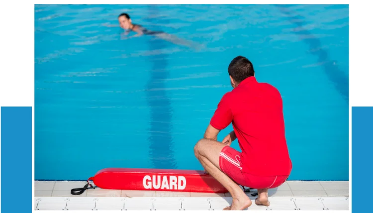 a lifeguard on the poolside watching a swimmer