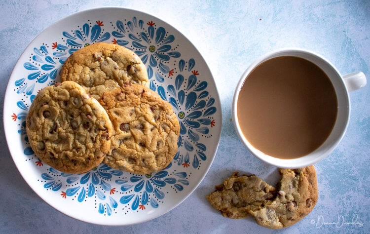 top view of 3 cookies on patterned plate, next to cup of coffee