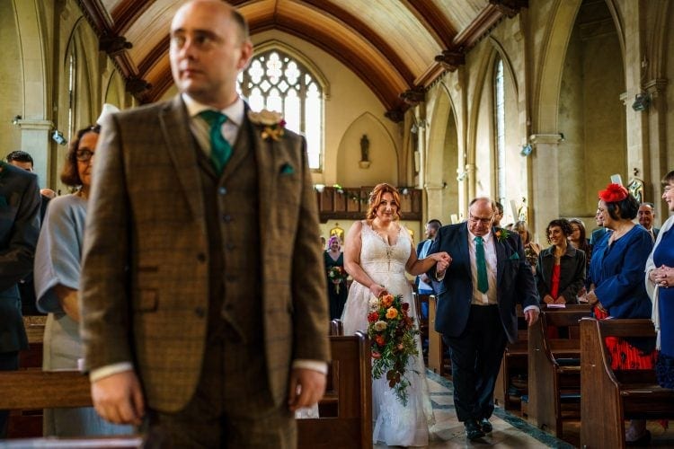 bride looking towards the groom as she walks down the aisle