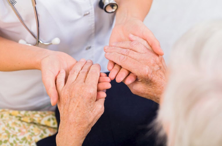 A nurse holding a senior patient hands