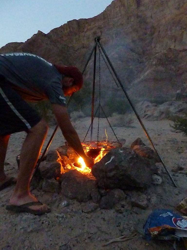 As night falls, Gary stirs the campfire on our Kayak Hoover Dam Black Canyon adventure.