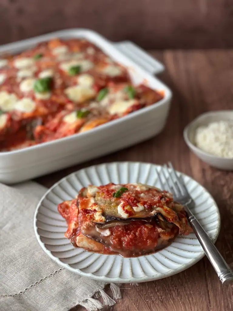 Plate of Eggplant Parm on a table with baking dish in background
