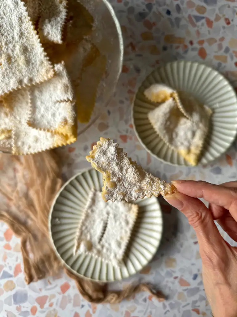 crostoli on plates with an hand holding a piece