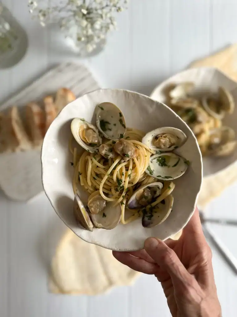 Plate of spaghetti clams held by an hand
