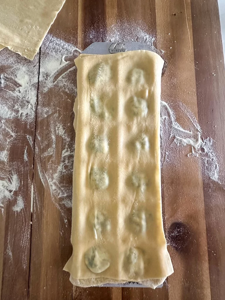 Closing the ravioli mold with another sheet of pasta