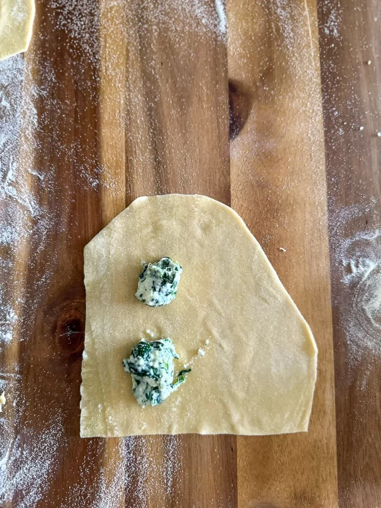 pasta sheets with some ravioli filling spaced.