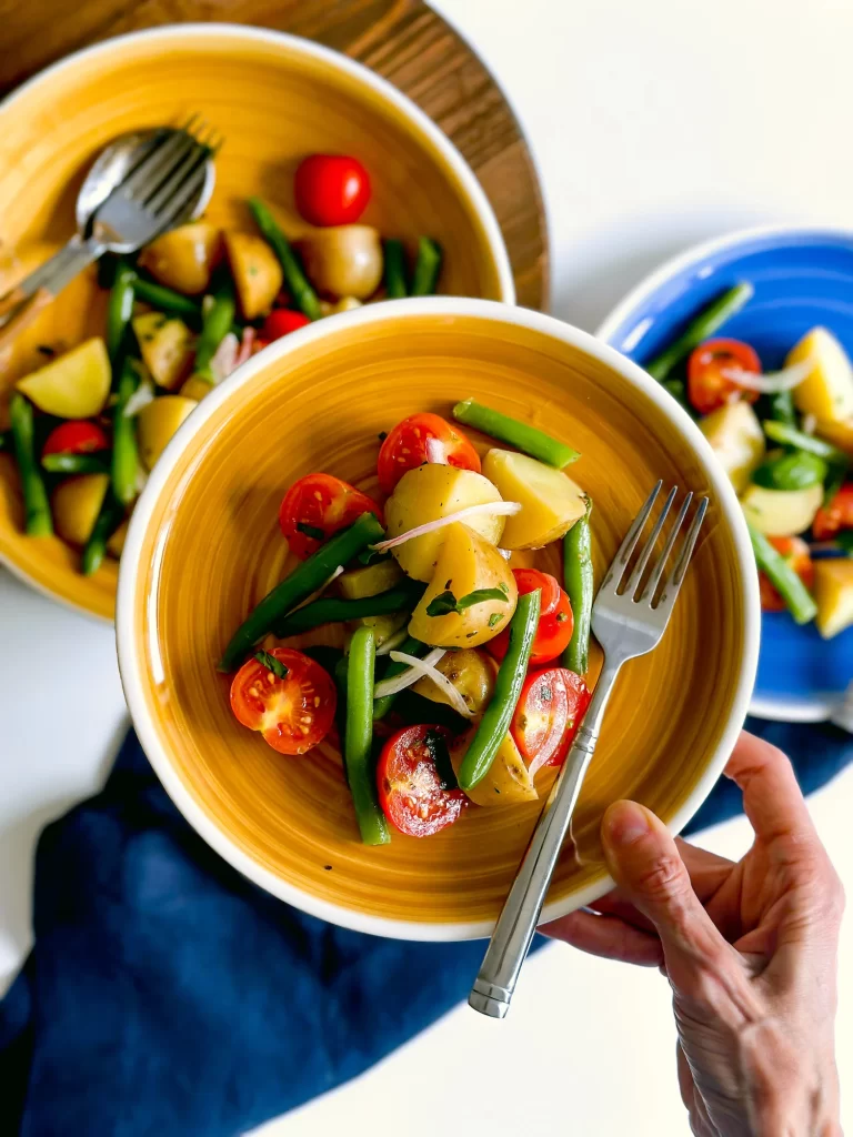 Italian potato salad in plate in hand over a table