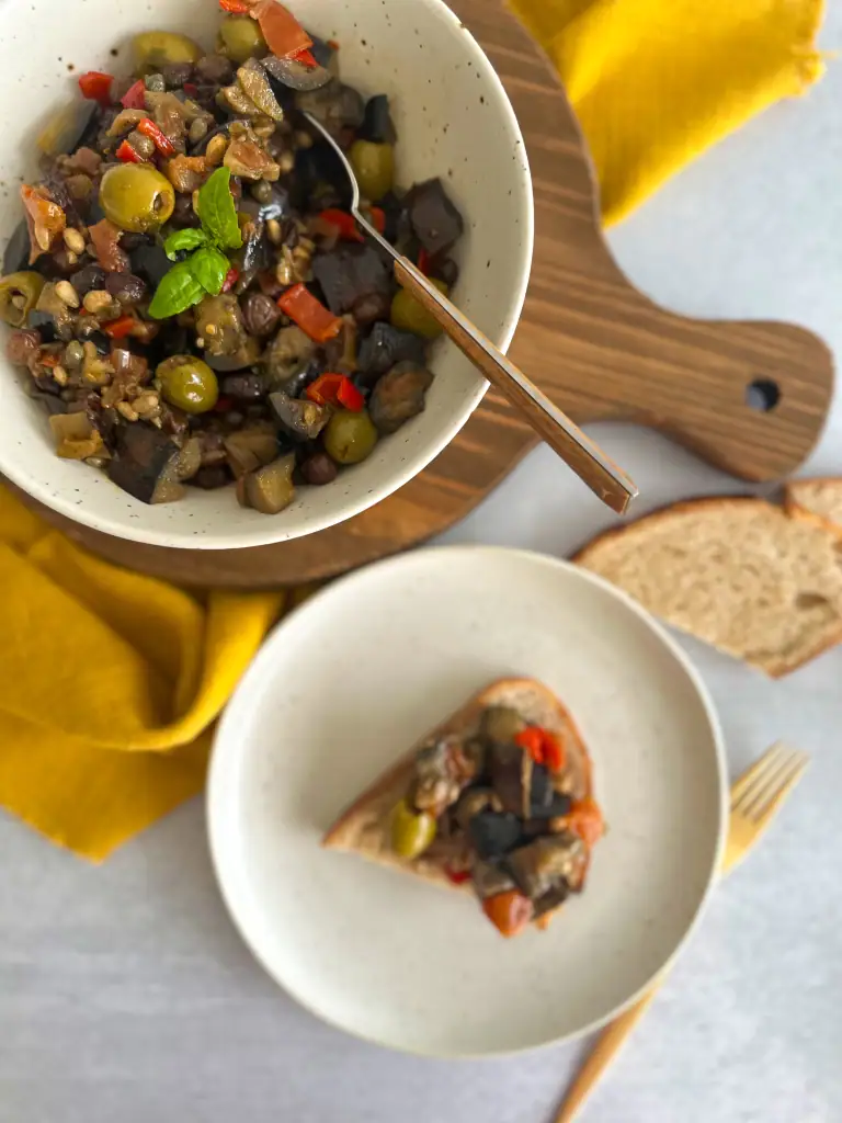 full view of a bowl of caponata and a plate where caponata is topping a bruschetta