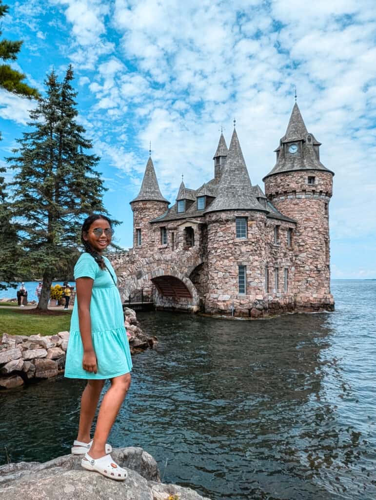 Girl standing on rock with Boldt Castle Thousand Islands behind her in Upstate New York with kids