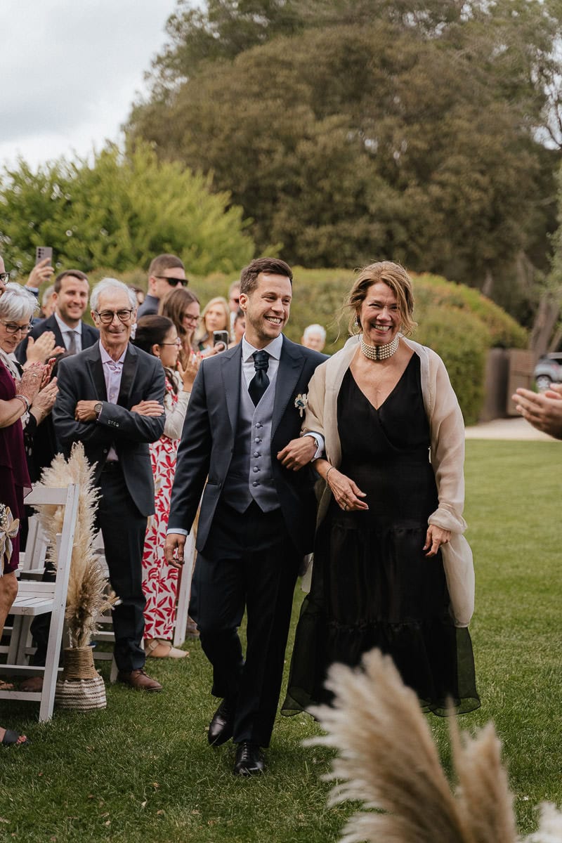 Groom walking along the isle with his mother
