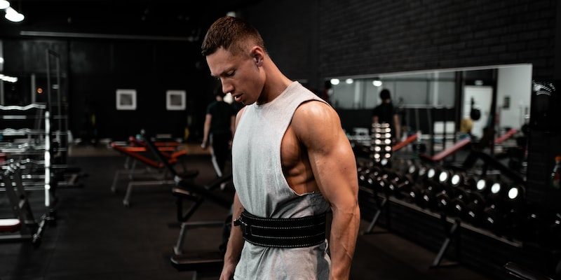 man in white tank top holding bumper plate