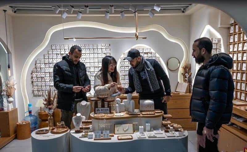 Customer browsing fashion jewelry at a Yiwu market stall during a buying trip
