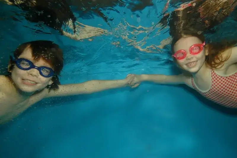 2 young children swimming confidently underwater with their eyes open, demonstrating expert breath control and water confidence.