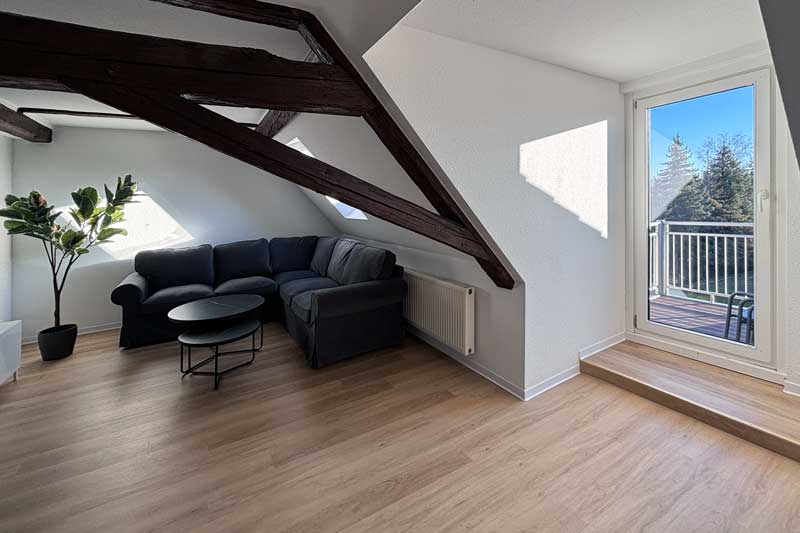 Blick vom Wohnzimmer auf das Sofa und den Balkon in Ferienwohnung K9