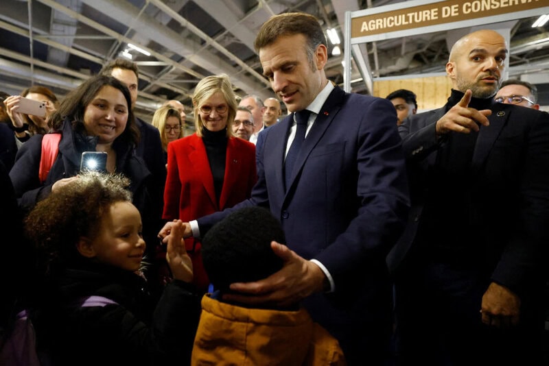 France's President Emmanuel Macron (C) interacts with young attendees during the opening day and inauguration of the 61st International Agricultural Fair (Salon de l'Agriculture) at the Porte de Versailles exhibition centre in Paris on February 22, 2025. The 2025 edition of the SIA (Salon International de l'Agriculture) Agriculture is held in Paris from February 22, to March 2, 2025. (Photo by Sarah Meyssonnier / POOL / AFP)