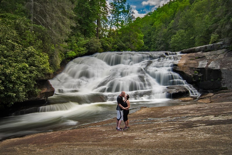 Brooke and Buddy kissing at the base of triple falls in Dupont State Forest north carolina trying to recreate a photo from their first trip