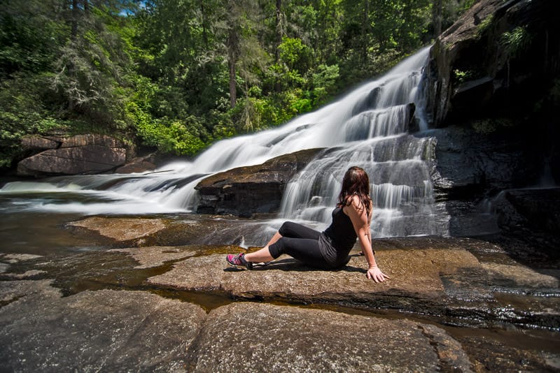 Brooke sitting on rocks at the base of triple falls in north carolina