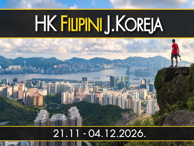 Muškarac stoji na stenovitoj litici i posmatra panoramu nebodera Hongkonga