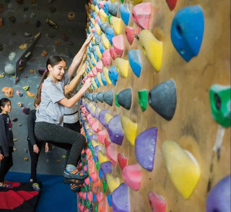 A youth climber focuses on technique while traversing across a grid of colorful holds.