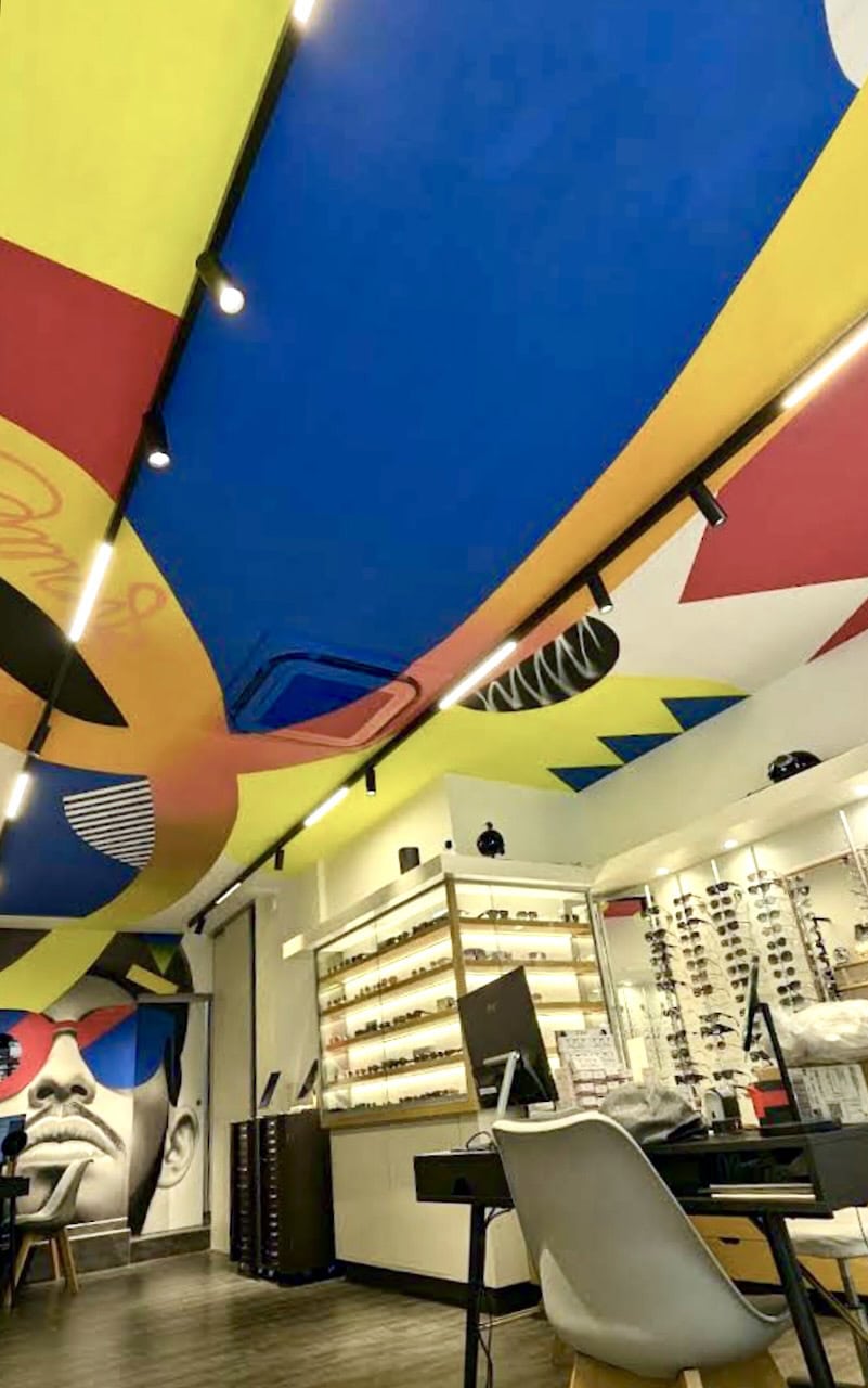 Plafond de boutique peint en street art : grands aplats bleus, jaunes et rouges, rayures et motifs graphiques