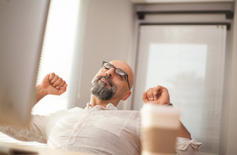 A man with no hair stretching his shoulder
