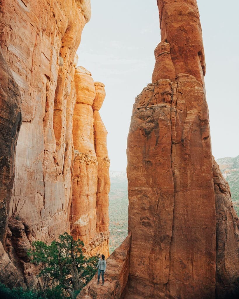 female hiker walking around the orange pillar at the top of cathedral rock vortex