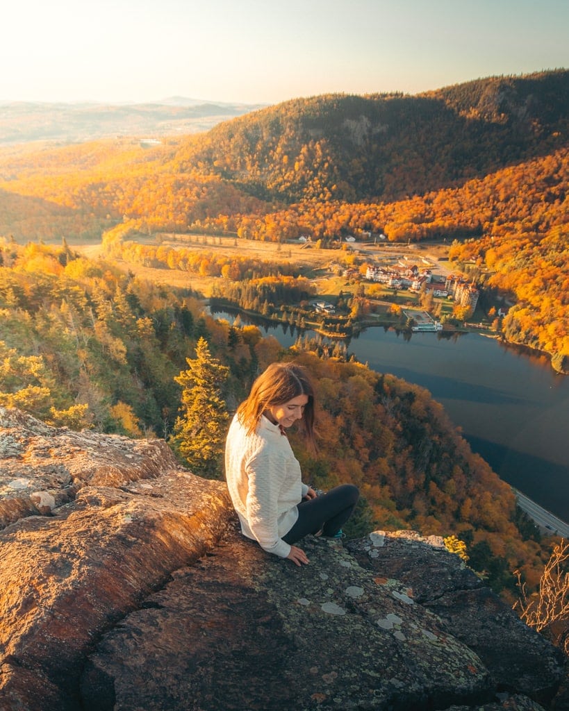 Girl sitting on top of Table Rock New Hampshire surrounded by fall foliage